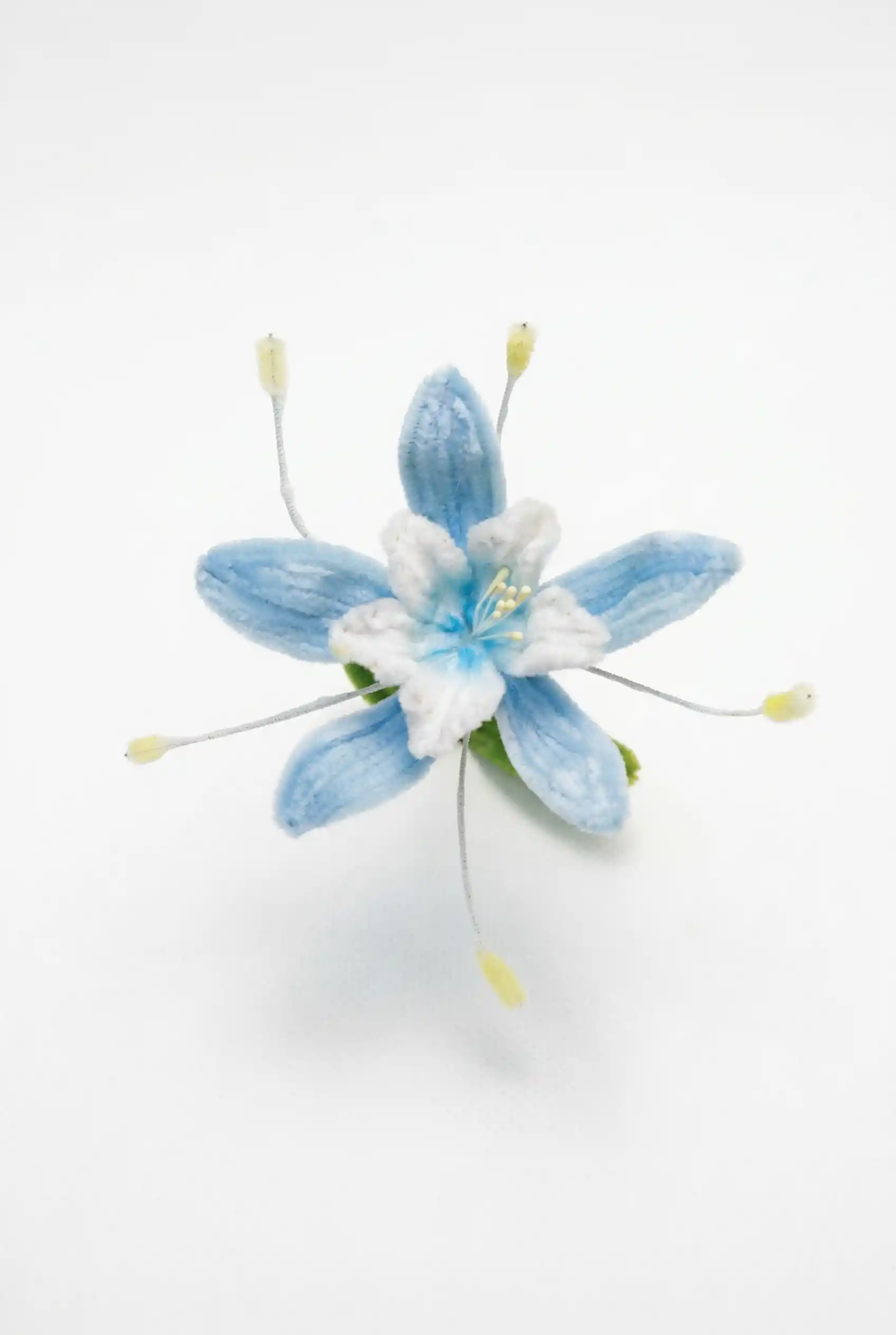 Top-down view of a finished handmade Blue Star flower (Tweedia) soft sculpture by Glint Garden, featuring azure petals and white center.