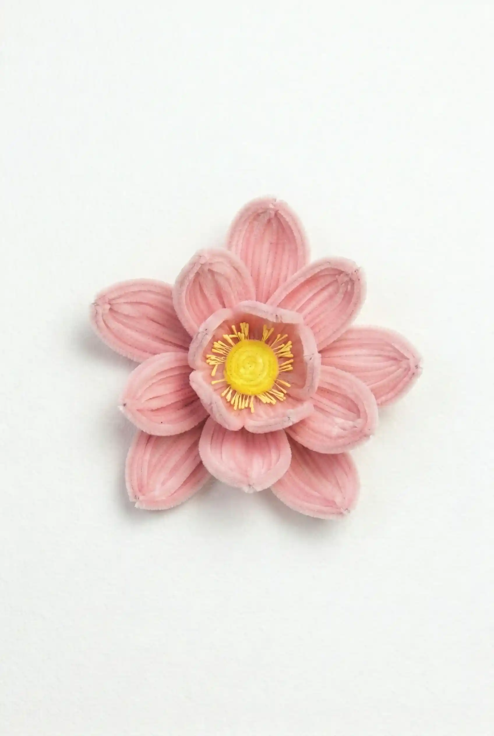 Top-down view of a finished artisan-made pink lotus flower with a vibrant yellow center.