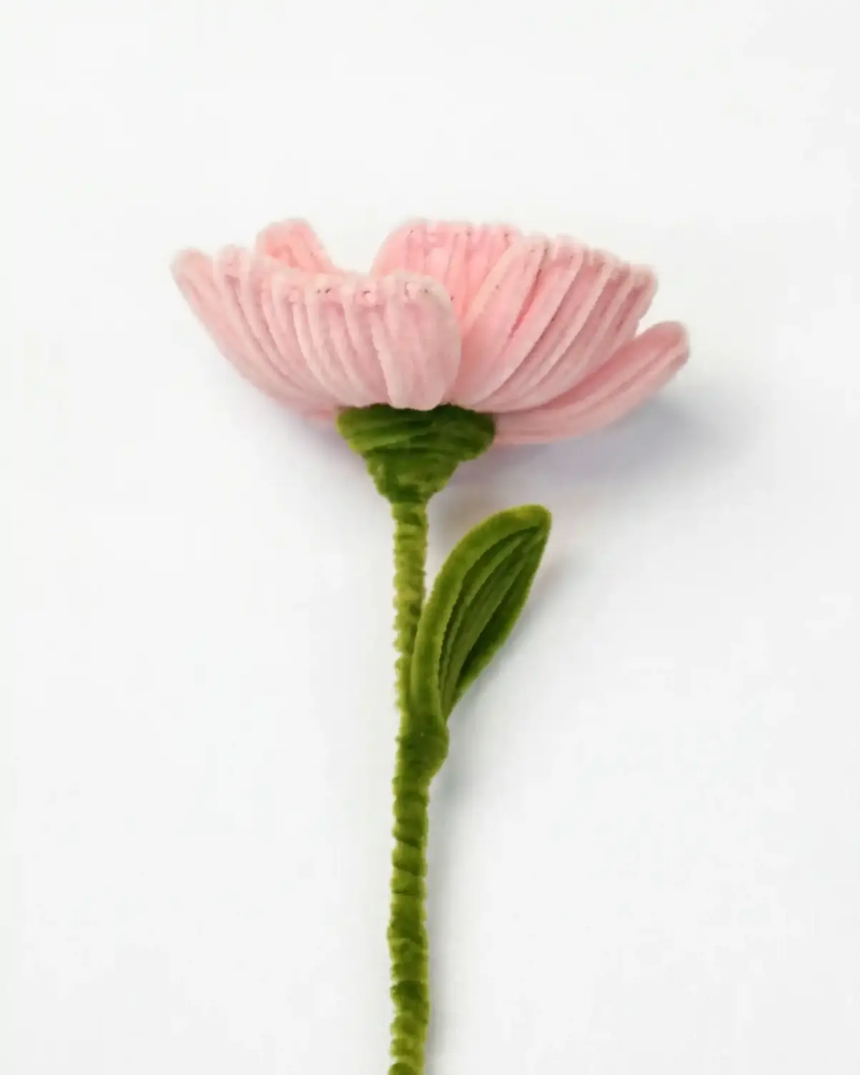 Side profile of a finished artisan-made pink Peony with a single green leaf on a long stem, ready for home decor.