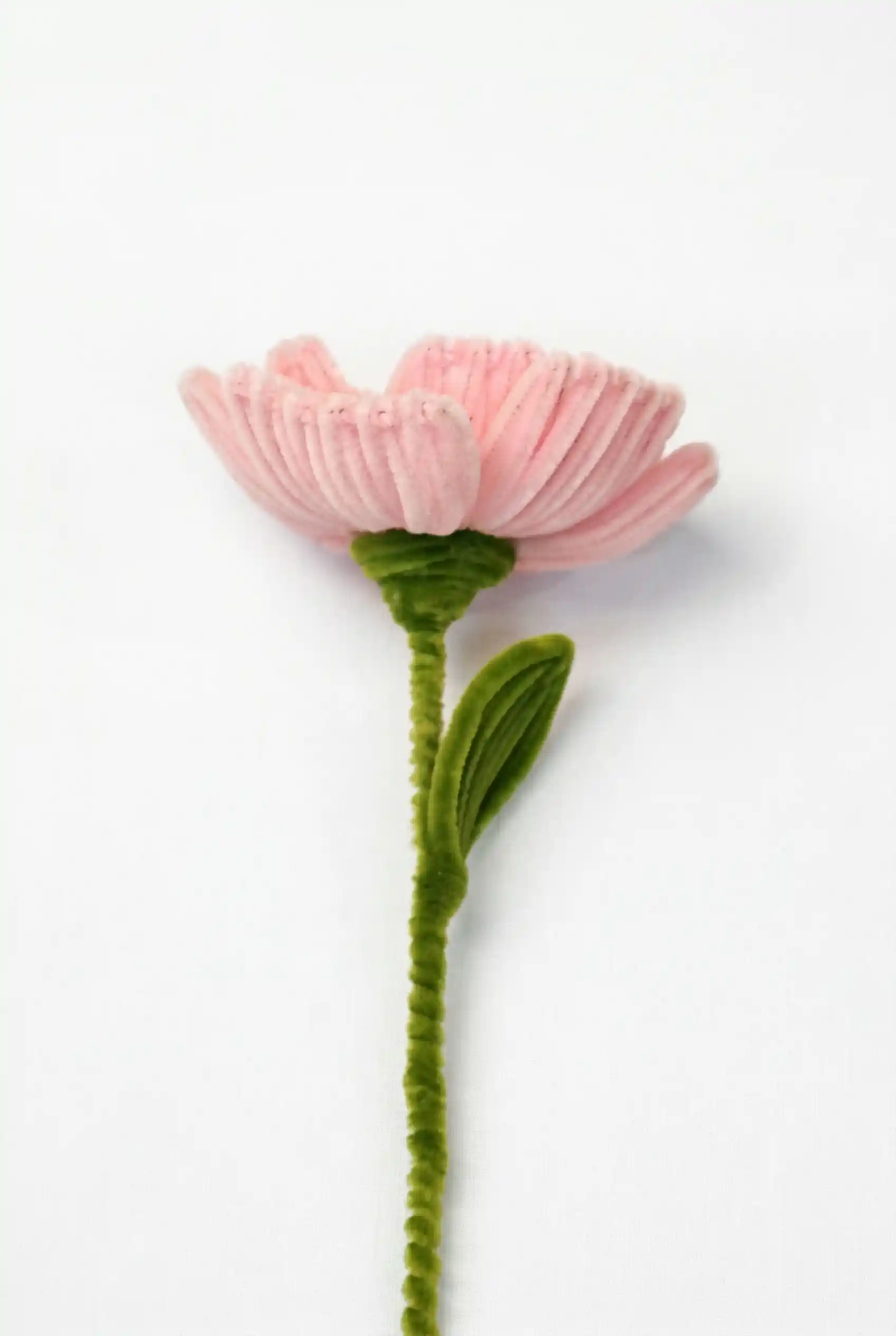 Side profile of a finished artisan-made pink Peony with a single green leaf on a long stem, ready for home decor.