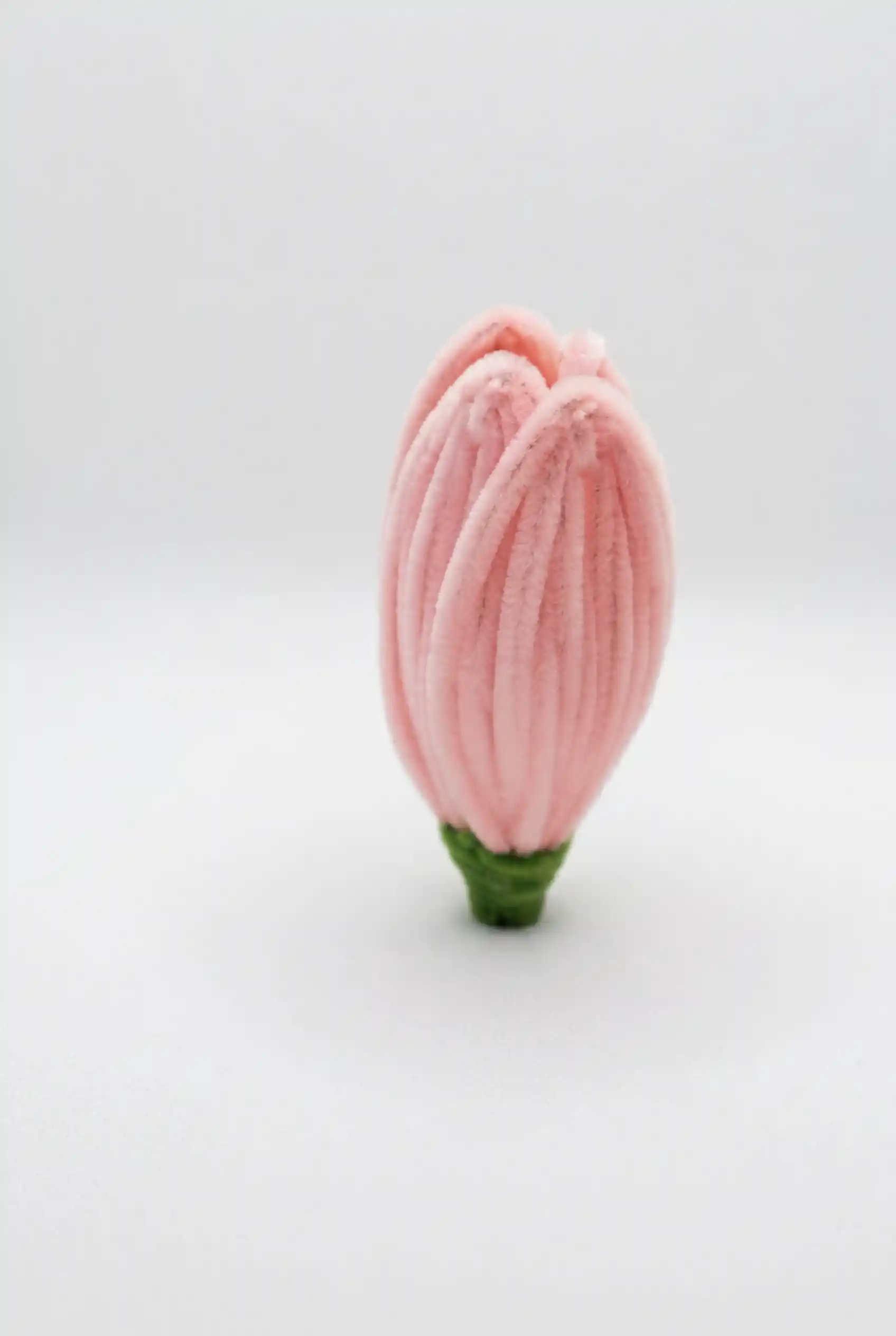 Close-up of a finished pink lotus bud soft sculpture, showing the intricate hand-sculpted velvet petals.