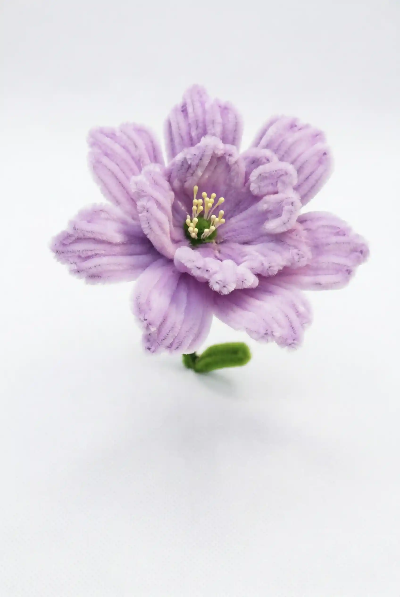Close-up of a finished handmade lavender Ranunculus soft sculpture by Glint Garden, showing dense, layered velvet petals.
