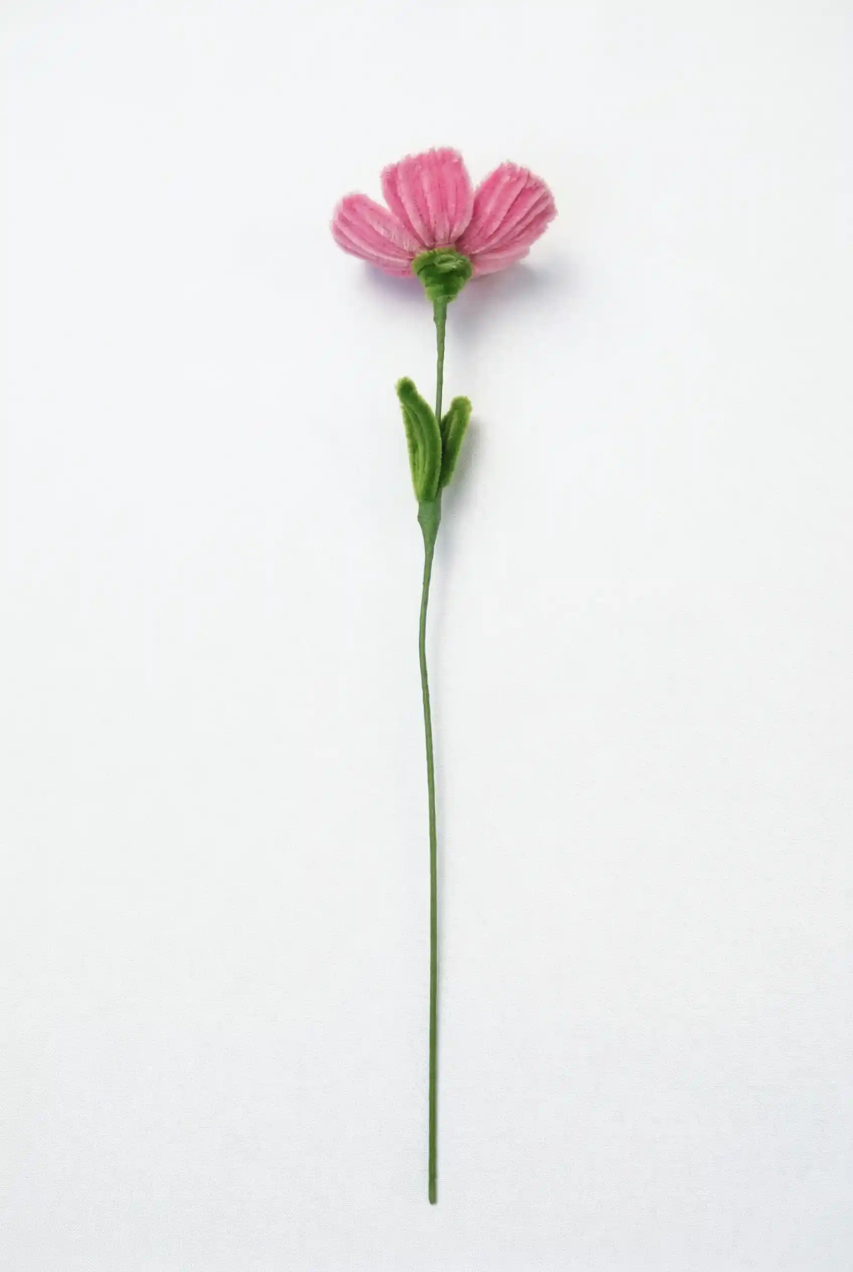 Side view of a finished artisan-made pink poppy flower with green leaves on a long stem, a whimsical home decor piece.
