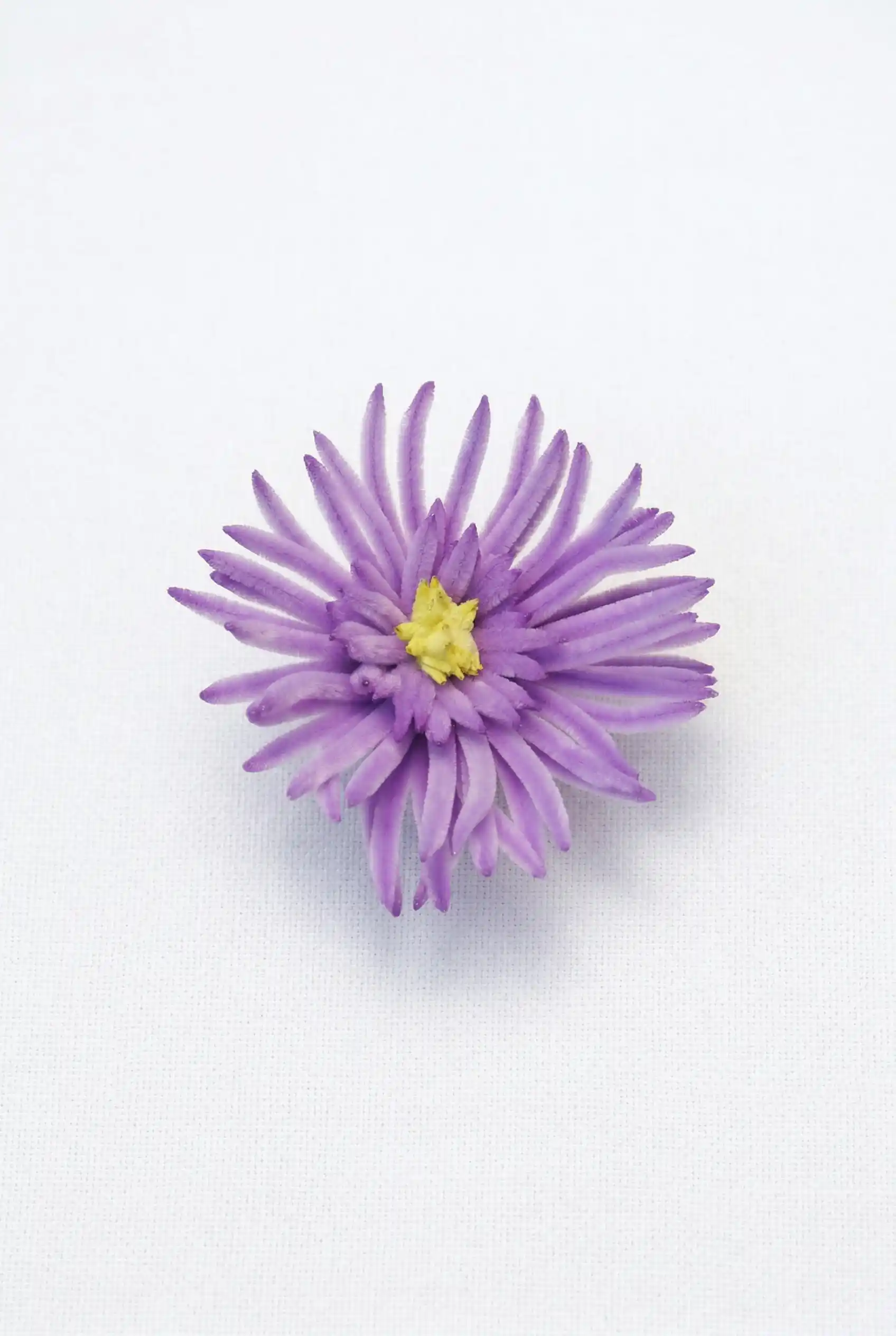 Close-up of a finished handmade purple spider mum soft sculpture, highlighting the intricate needle-like petals and yellow center.