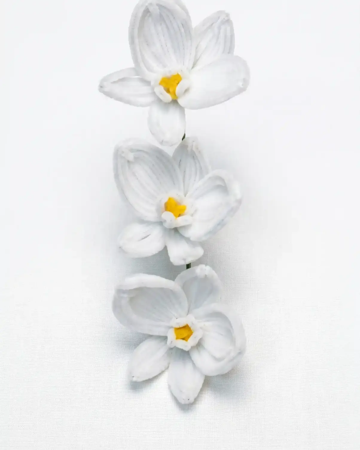 Front view of a finished handmade white Phalaenopsis orchid with three blooms and yellow centers by Glint Garden.