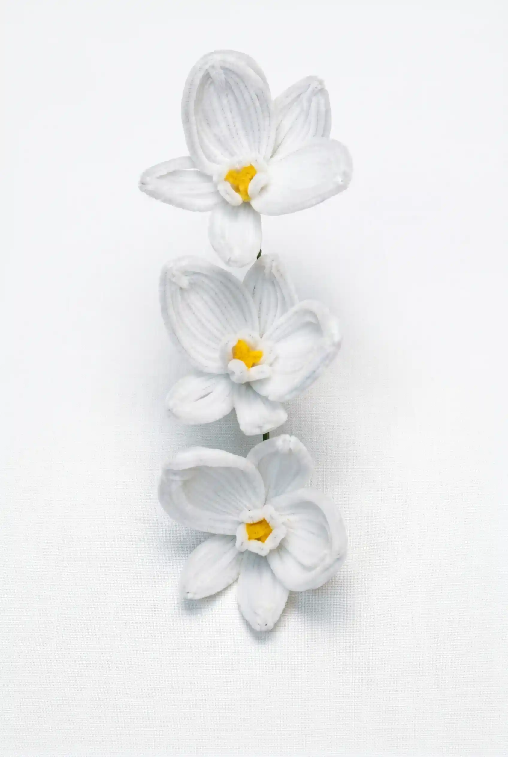 Front view of a finished handmade white Phalaenopsis orchid with three blooms and yellow centers by Glint Garden.