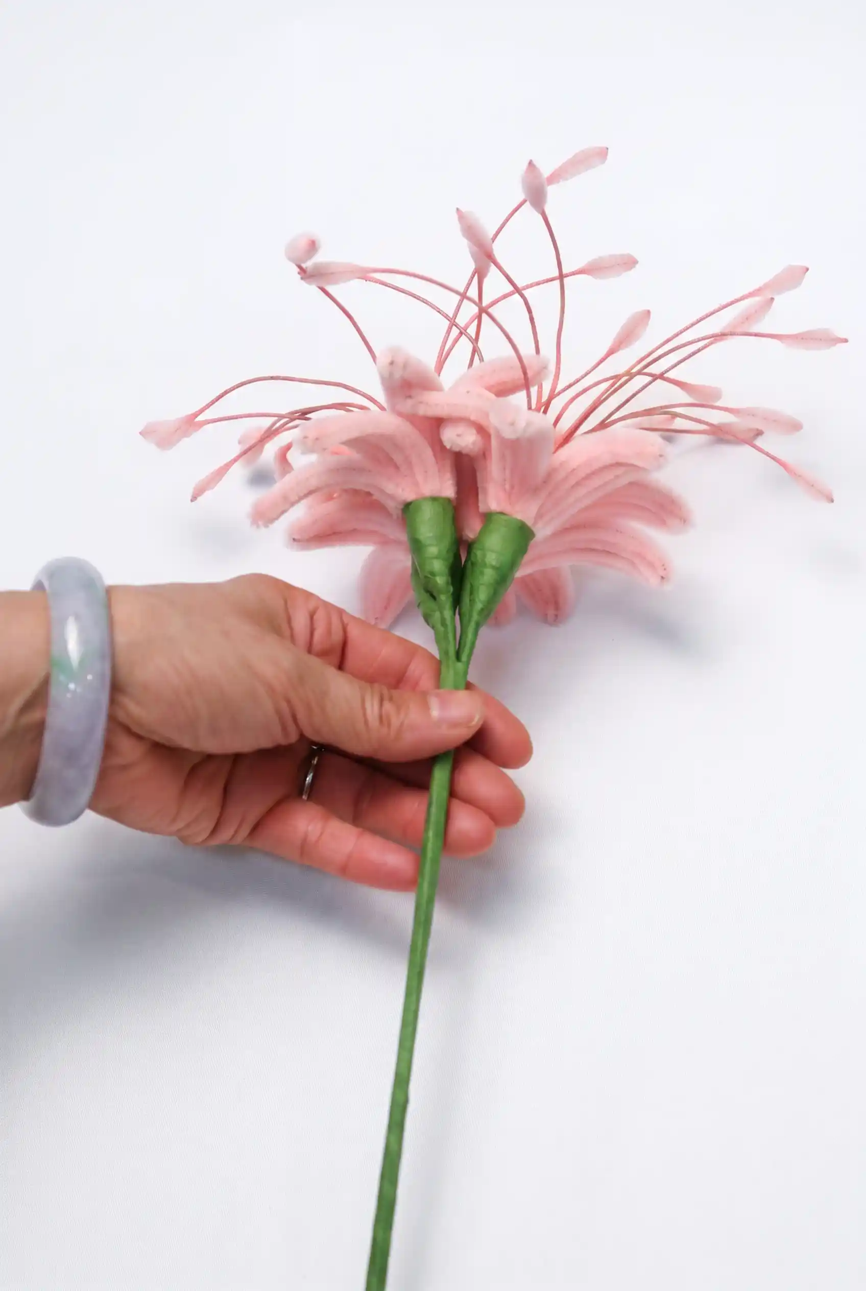a finished handmade pink spider lily (Lycoris) soft sculpture by Glint Garden, featuring delicate curling petals and long stamens.
